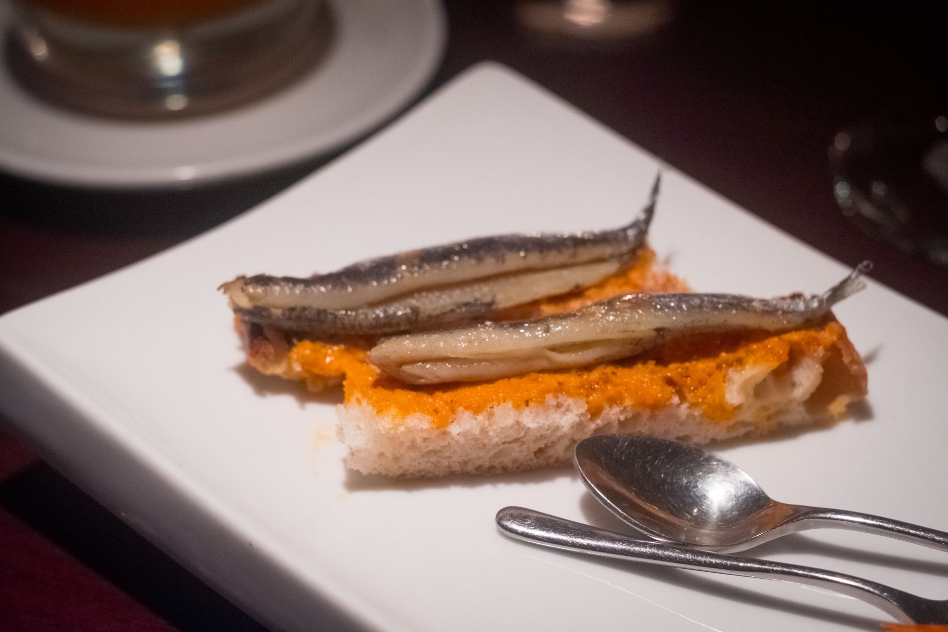 La esencia de la tapa catalana: Tostada con anchoas y salsa, fotografía gastronómica por Boca Studio BCN Tapa de boquerones en anchoas sobre tostada con salsa romesco, cocina tradicional catalana en Barcelona