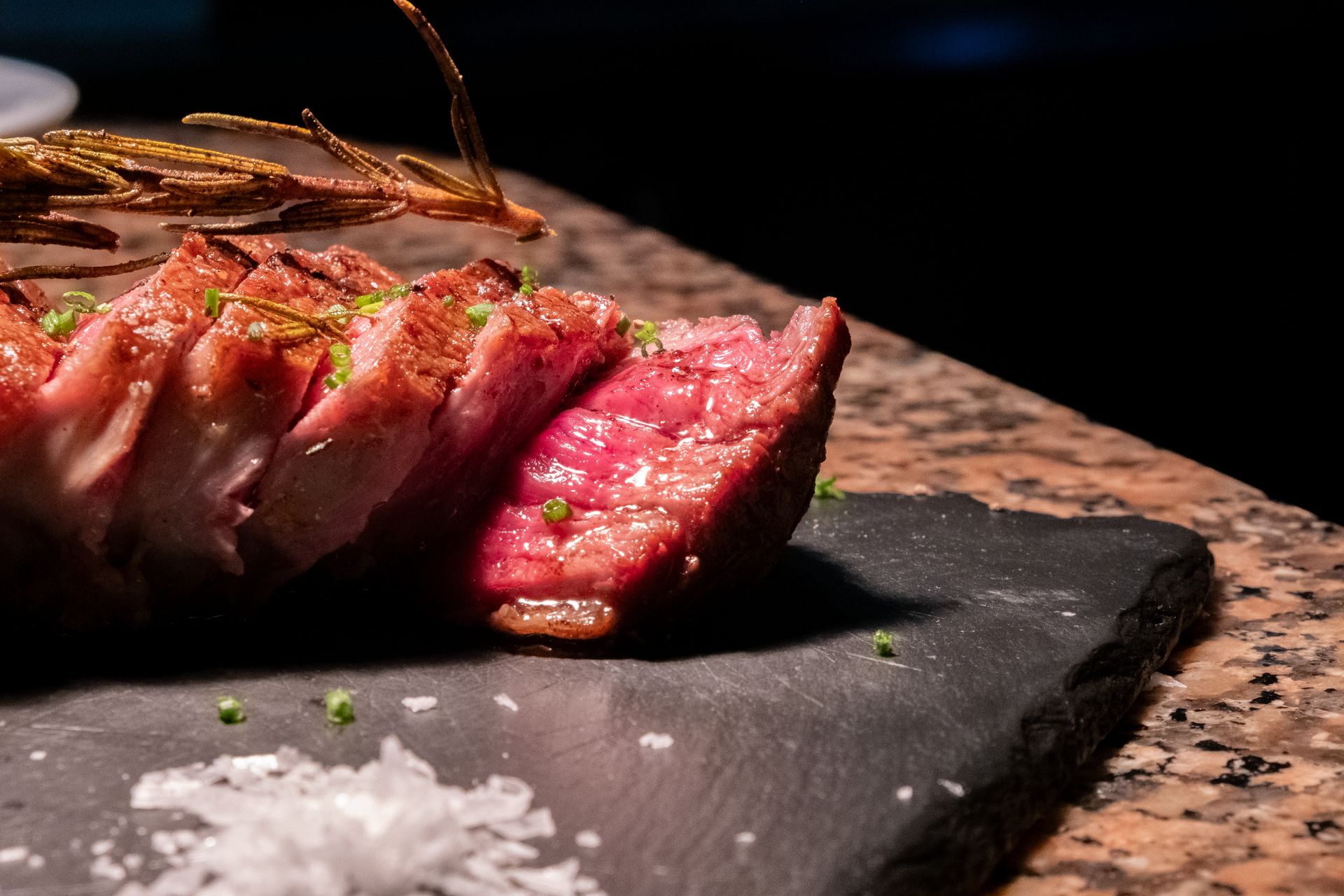 La perfección en la carne: Placer carnívoro capturado por Boca Studio BCN Corte de carne roja a la brasa, punto perfecto con sal y romero, fotografía en Barcelona