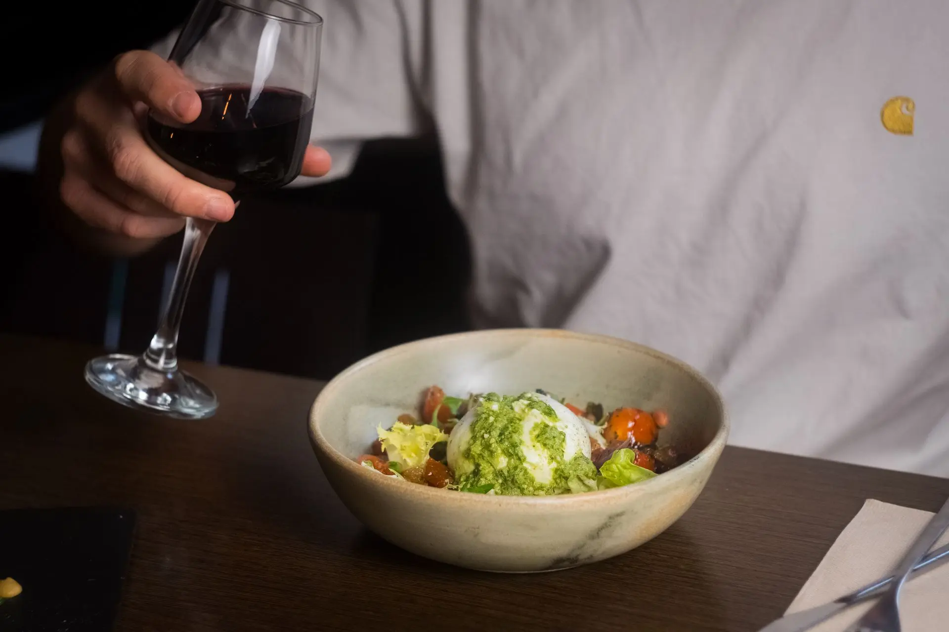Comensal disfrutando plato fresco con pesto y copa de vino tinto, fotografía de experiencia en restaurante Barcelona