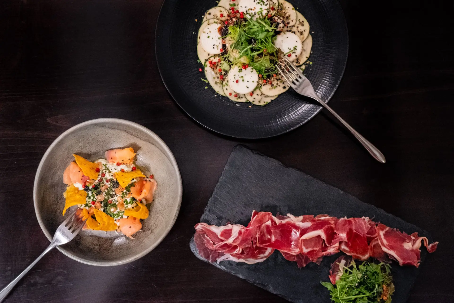 Surtido de tapas gourmet españolas: Jamón Ibérico, carpaccio y ceviche, fotografía de mesa de restaurante en Barcelona