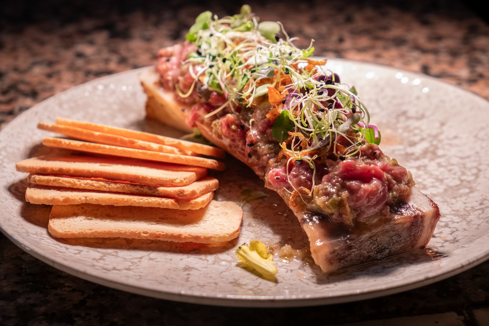 Creación culinaria de autor: Tuétano con tartar, un plato único fotografiado por Boca Studio BCN Tuétano asado con tartar de carne y brotes, plato innovador, fotografía gastronómica para restaurante Barcelona