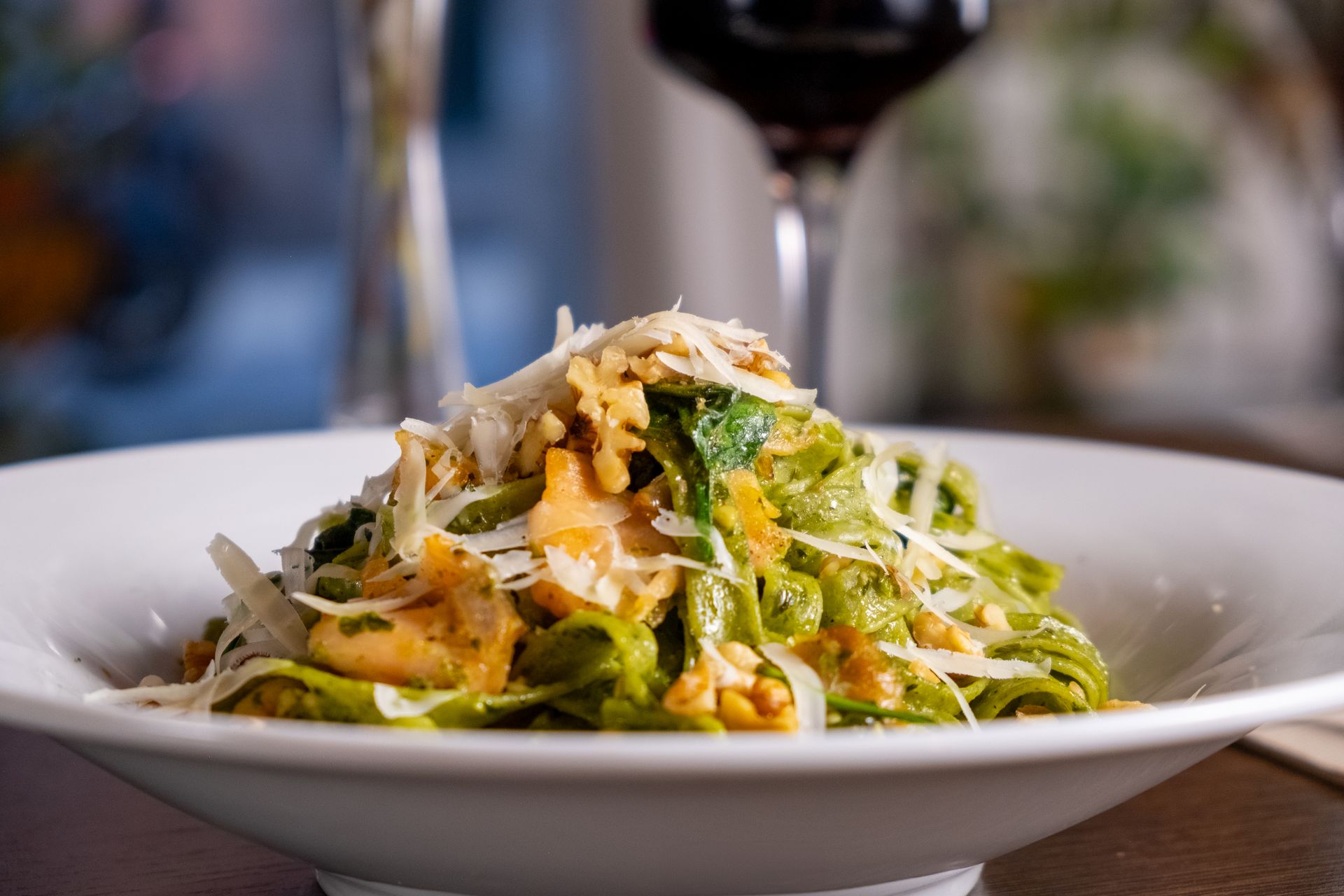 Delicia mediterránea: Pasta al pesto, salmón y parmesano, una creación de Boca Studio BCN Pasta verde al pesto con salmón y parmesano, plato italiano gourmet, fotografía de restaurante en Barcelona