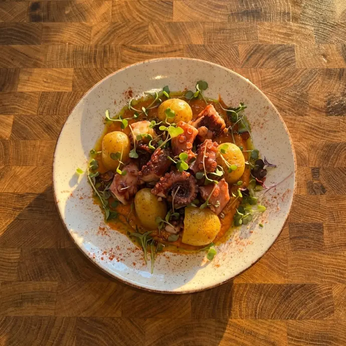 Foto profesional de un plato de pulpo con patatas para restaurantes creada con IA.